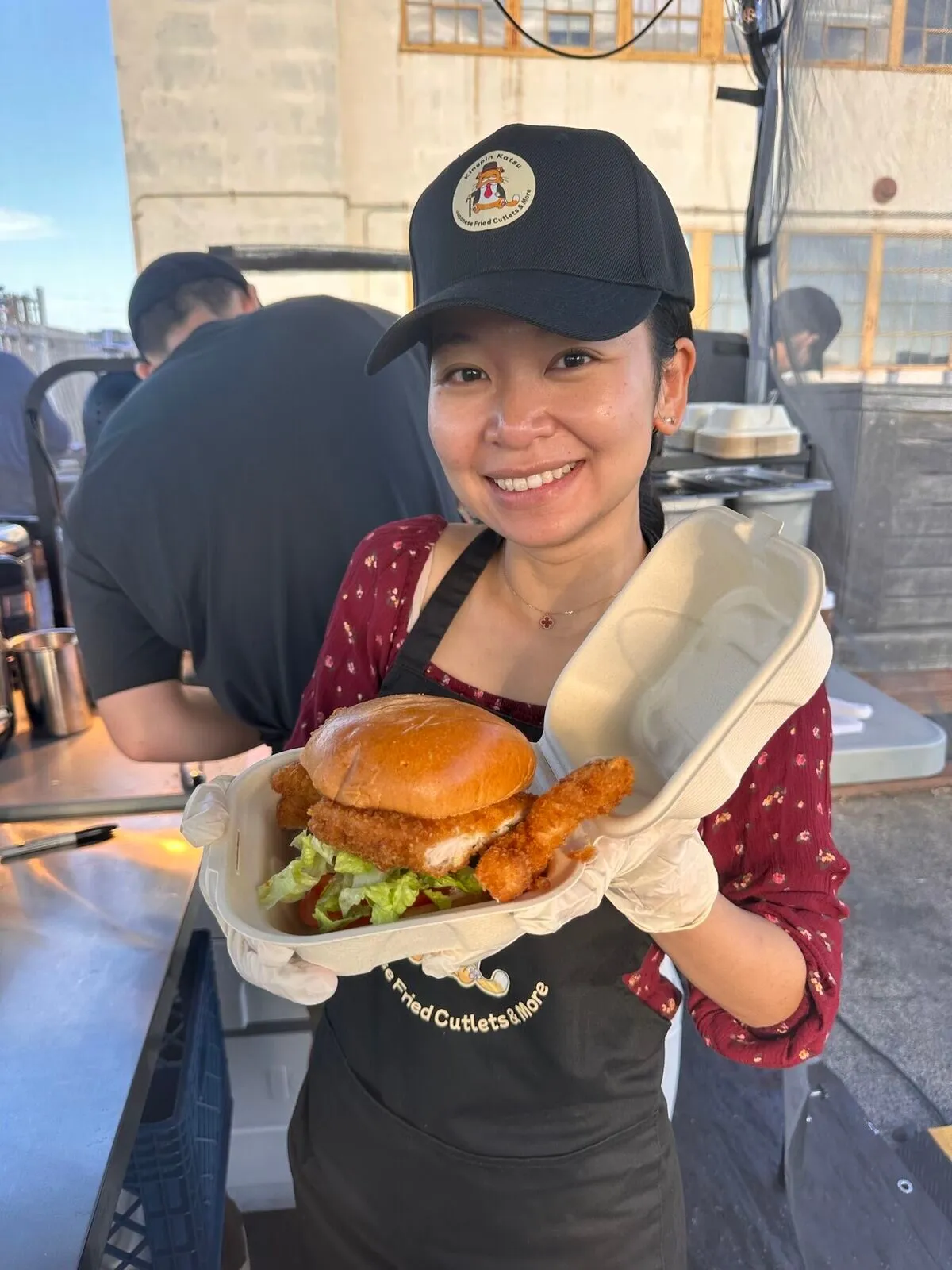 A crew member holding up a katsu burger